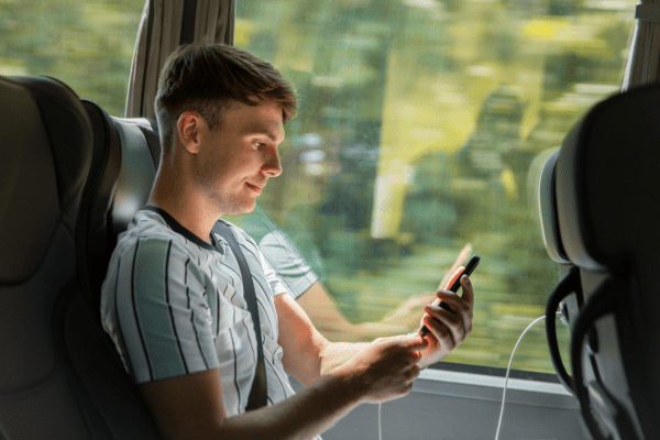 Man using USB charger on coach